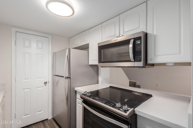 kitchen with white cabinetry, appliances with stainless steel finishes, and dark hardwood / wood-style flooring