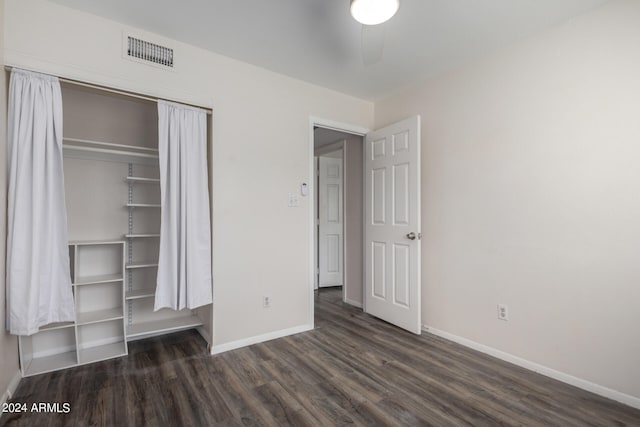 unfurnished bedroom with dark hardwood / wood-style flooring, a closet, and ceiling fan