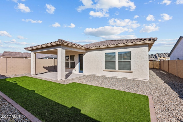 rear view of property featuring stucco siding, a fenced backyard, a tiled roof, and a patio