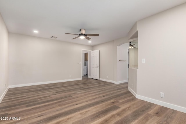 empty room with baseboards, recessed lighting, wood finished floors, arched walkways, and a ceiling fan