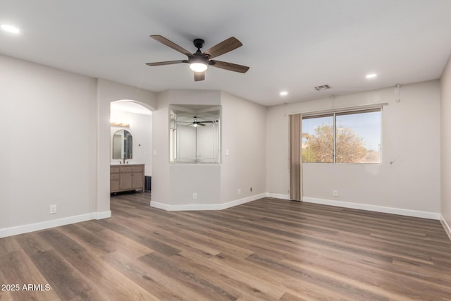 empty room with recessed lighting, baseboards, arched walkways, and wood finished floors