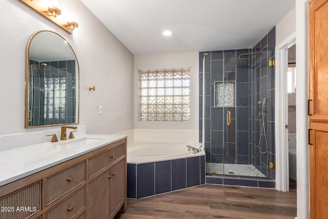 full bath with toilet, a garden tub, a stall shower, wood finished floors, and vanity