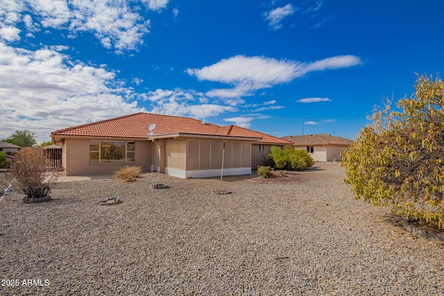 rear view of property with a patio, a tiled roof, and a sunroom