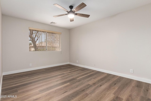 spare room featuring visible vents, ceiling fan, baseboards, and wood finished floors