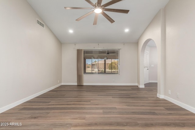 spare room with visible vents, lofted ceiling, arched walkways, and wood finished floors