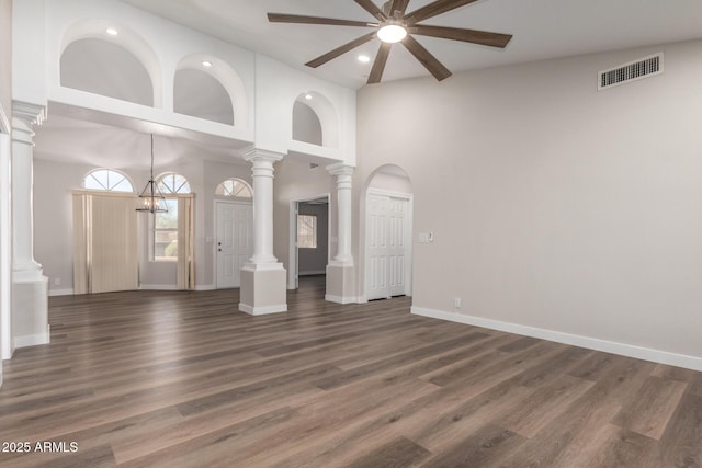 unfurnished living room featuring dark wood finished floors, visible vents, and ornate columns