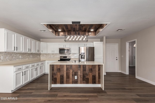 kitchen with visible vents, stainless steel appliances, light countertops, white cabinets, and tasteful backsplash