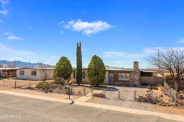 single story home featuring a fenced front yard, a mountain view, and a gate