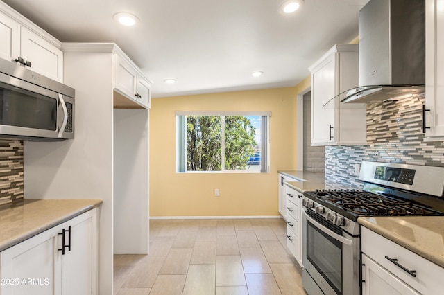 kitchen featuring wall chimney range hood, light countertops, recessed lighting, appliances with stainless steel finishes, and white cabinetry