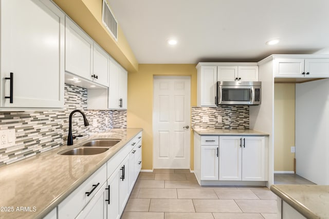 kitchen featuring visible vents, recessed lighting, a sink, white cabinetry, and stainless steel microwave