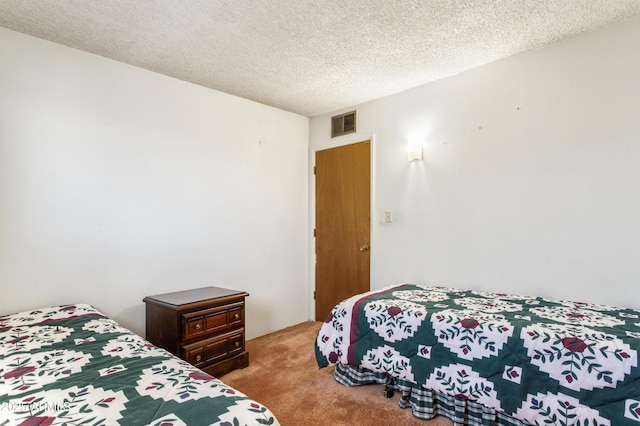 bedroom with carpet, visible vents, and a textured ceiling