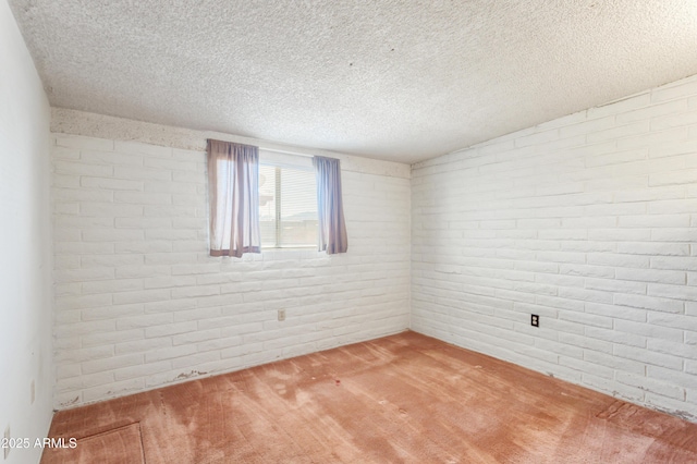 unfurnished room featuring carpet, brick wall, and a textured ceiling