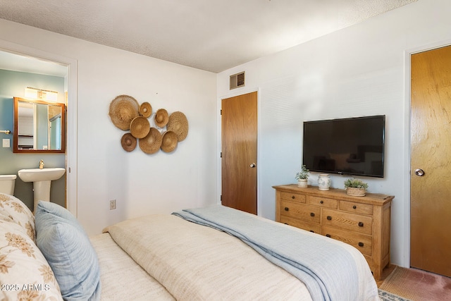 bedroom with visible vents, ensuite bath, and carpet flooring