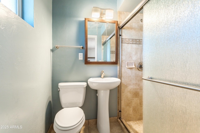 bathroom featuring a shower stall, toilet, and a sink