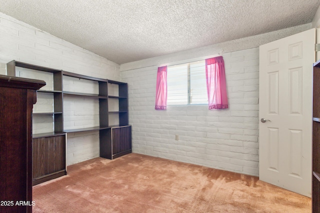 unfurnished bedroom with brick wall, carpet floors, and a textured ceiling