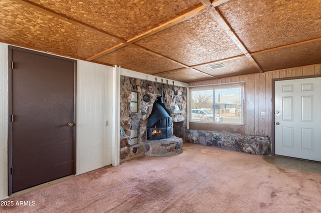 unfurnished living room with a wood stove, visible vents, and carpet flooring