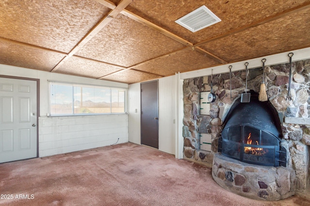 unfurnished living room featuring visible vents, carpet floors, and a wood stove