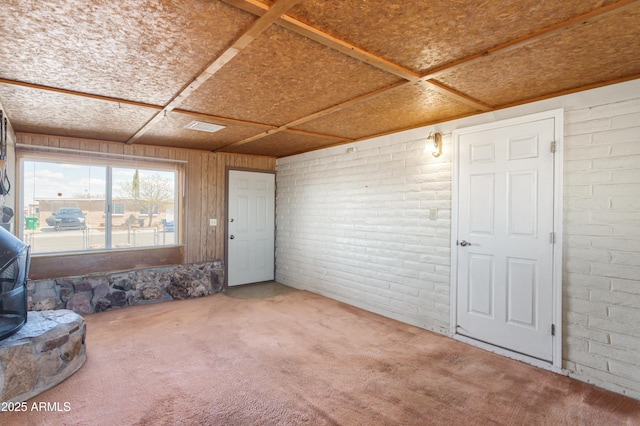 interior space featuring brick wall, a wood stove, and carpet floors