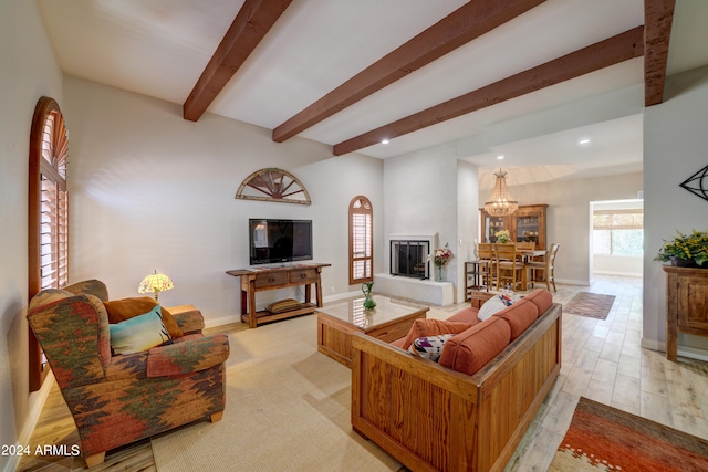 living room with an inviting chandelier, light hardwood / wood-style floors, and beam ceiling