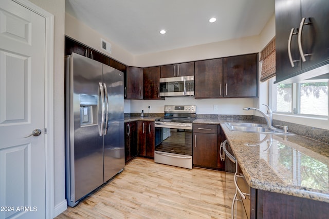 kitchen featuring light hardwood / wood-style floors, light stone counters, stainless steel appliances, dark brown cabinetry, and sink