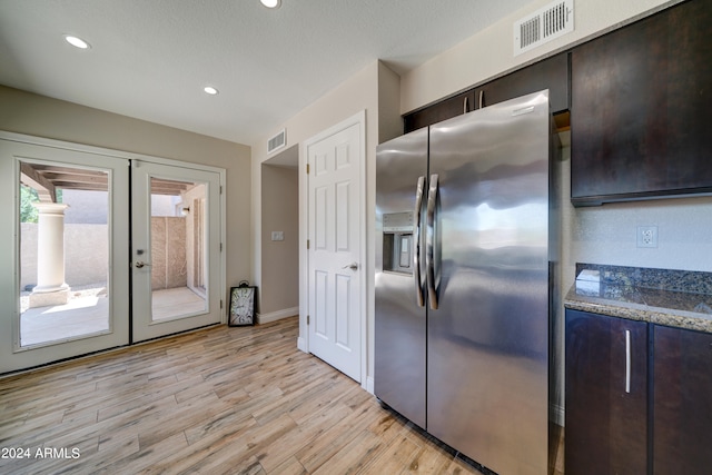 kitchen featuring light hardwood / wood-style floors, stainless steel fridge with ice dispenser, dark brown cabinetry, dark stone countertops, and french doors