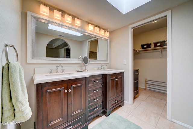 bathroom featuring tile patterned flooring, vanity, and a skylight