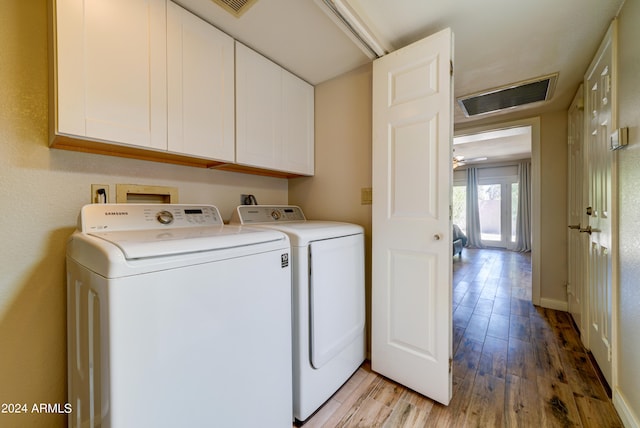 laundry area with washing machine and clothes dryer, light hardwood / wood-style flooring, and cabinets