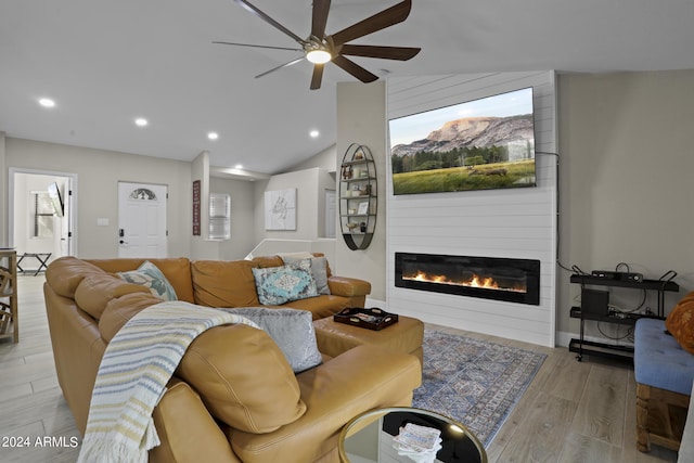 living room featuring ceiling fan, lofted ceiling, a fireplace, and light hardwood / wood-style floors