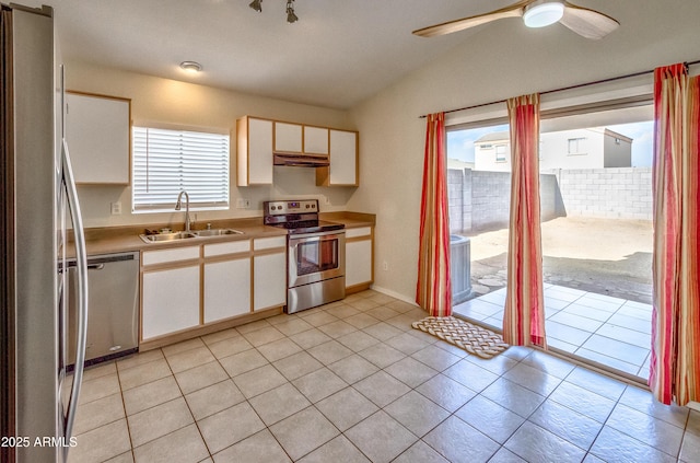 kitchen featuring vaulted ceiling, appliances with stainless steel finishes, white cabinets, light tile patterned flooring, and sink