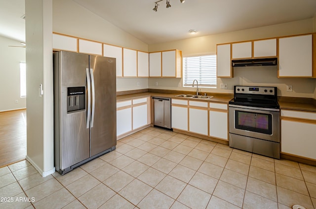 kitchen featuring vaulted ceiling, light tile patterned floors, white cabinetry, appliances with stainless steel finishes, and sink