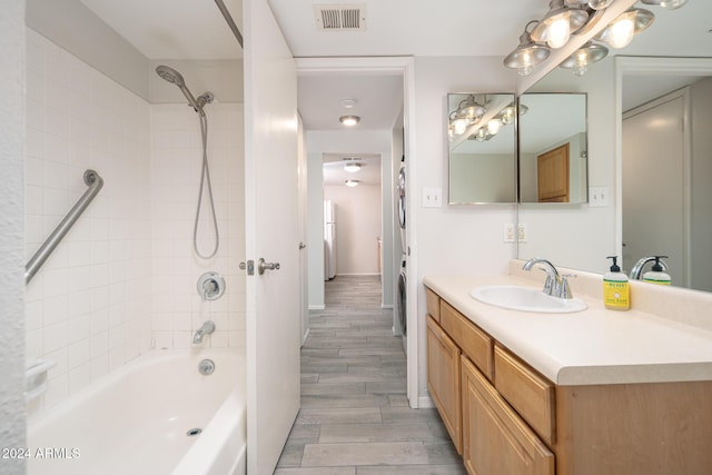 bathroom with hardwood / wood-style floors, vanity, and tiled shower / bath combo
