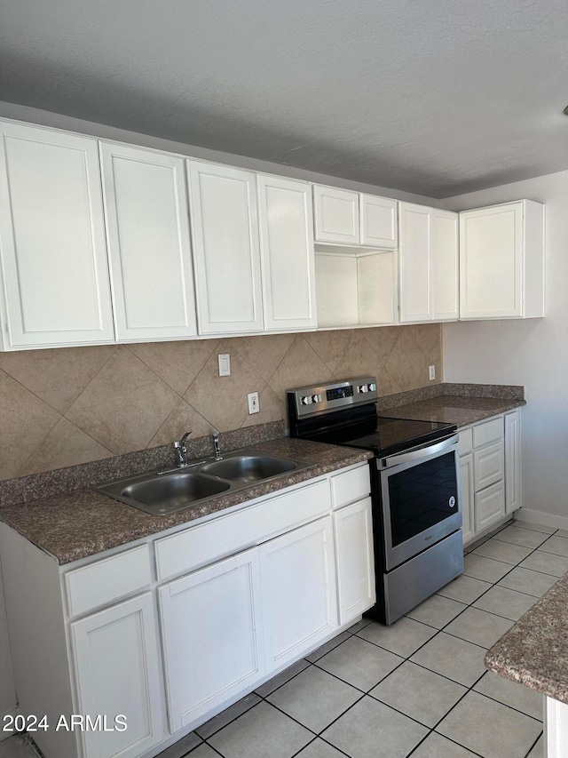 kitchen with tasteful backsplash, sink, light tile patterned floors, white cabinets, and stainless steel electric range oven