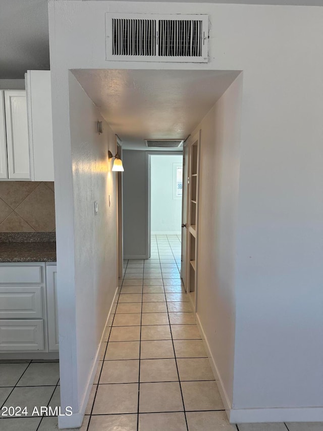 hall with light tile patterned floors and a textured ceiling