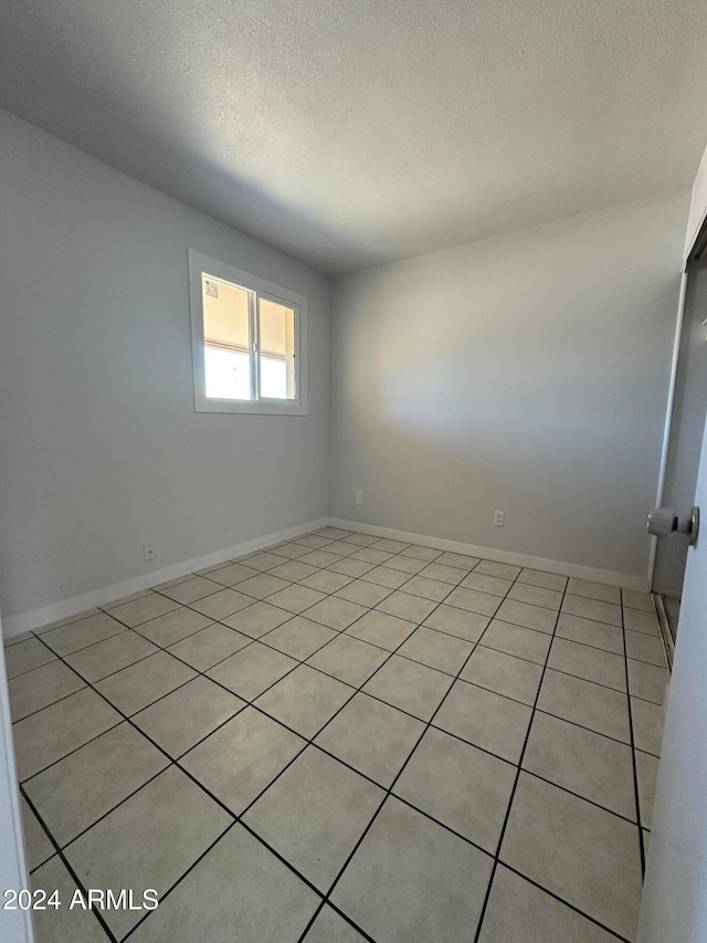 empty room with light tile patterned flooring and a textured ceiling