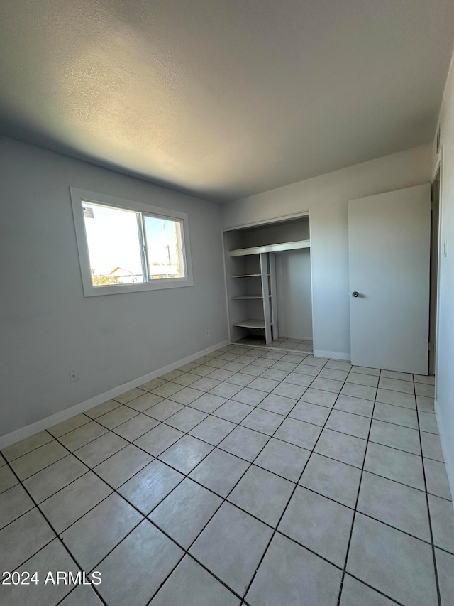 unfurnished bedroom with a closet, light tile patterned floors, and a textured ceiling