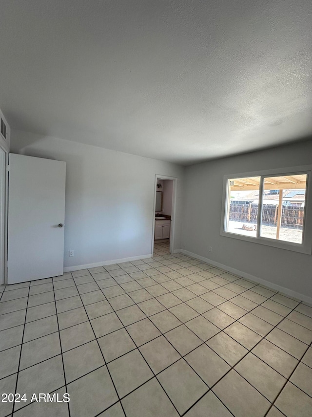 tiled empty room with a textured ceiling