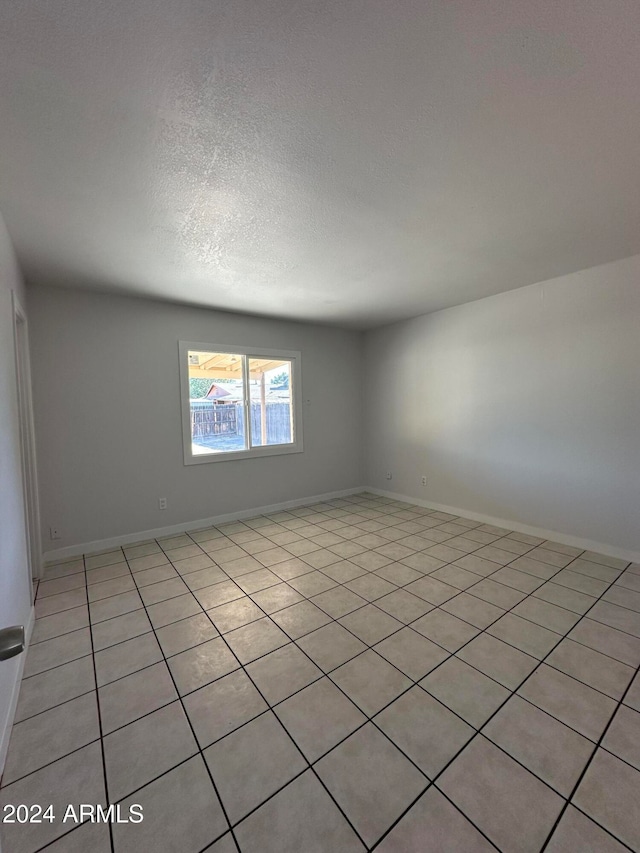 spare room featuring light tile patterned floors and a textured ceiling