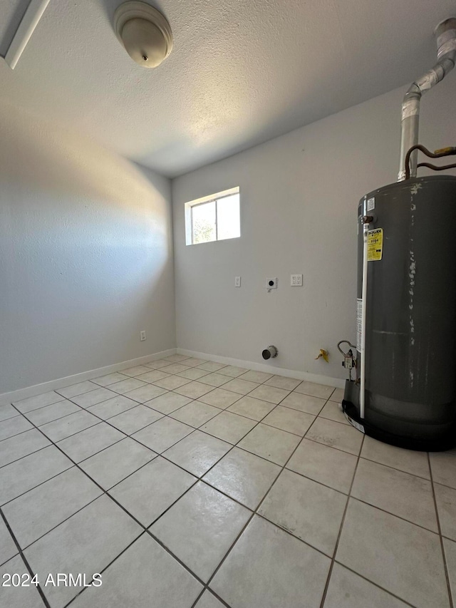 washroom featuring electric dryer hookup, light tile patterned floors, a textured ceiling, and water heater