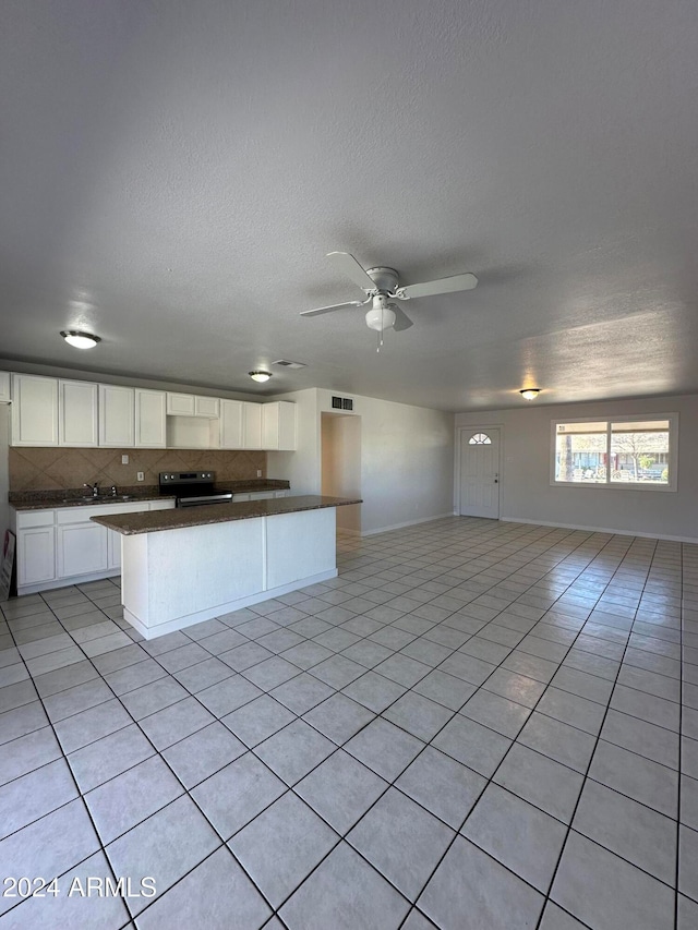 kitchen with backsplash, ceiling fan, stainless steel electric stove, white cabinetry, and light tile patterned flooring