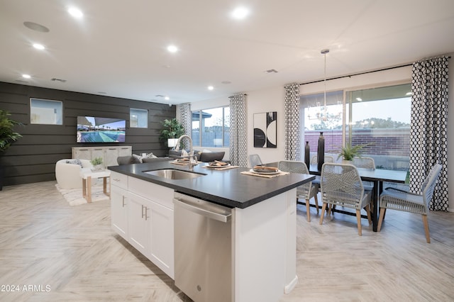 kitchen featuring dishwasher, a center island with sink, white cabinets, sink, and hanging light fixtures