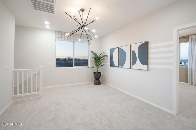 spare room featuring a notable chandelier and light colored carpet