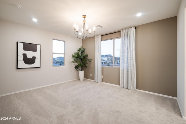 carpeted spare room featuring an inviting chandelier