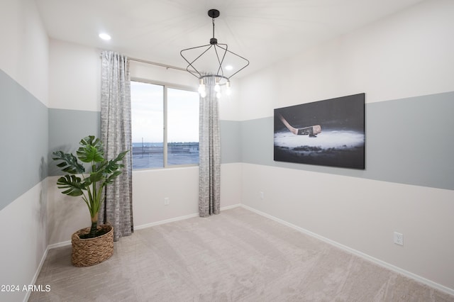 empty room with light carpet, a water view, and an inviting chandelier