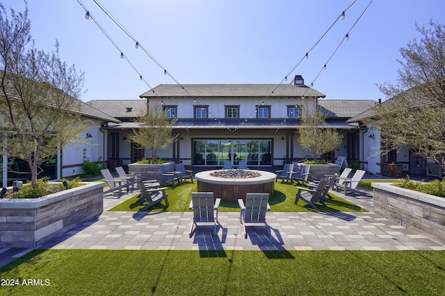 rear view of property featuring a patio area, a yard, and an outdoor fire pit