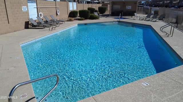 pool with a patio area and fence