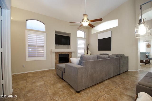 living area with baseboards, a ceiling fan, a fireplace, high vaulted ceiling, and light tile patterned flooring