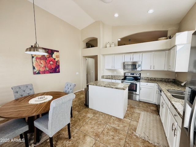 kitchen featuring white cabinets, a kitchen island, appliances with stainless steel finishes, light stone counters, and pendant lighting