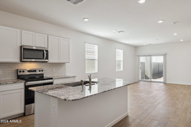 25484 W Graham Trl, Buckeye, AZ 85326 - kitchen with stainless steel appliances, light wood finished floors, tasteful backsplash, white cabinetry, and light stone countertops