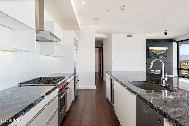 kitchen with tasteful backsplash, premium appliances, modern cabinets, wall chimney range hood, and a sink