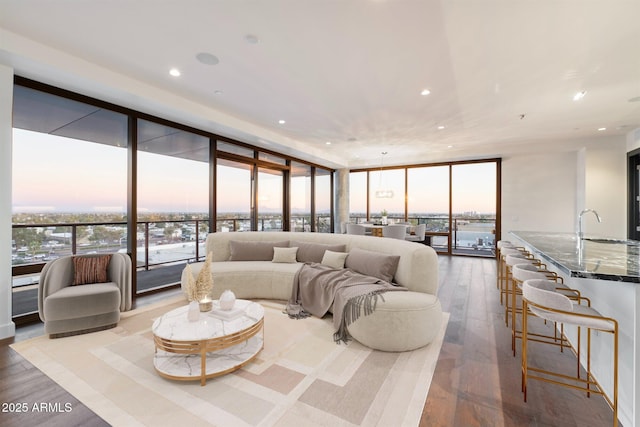 living room with a healthy amount of sunlight, hardwood / wood-style flooring, expansive windows, and recessed lighting